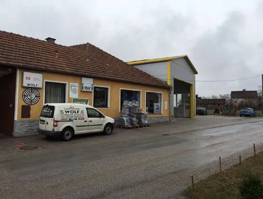 Fassade mit dem Schild WOLF, daneben Schilder von Stihl, davor der Firmenwagen