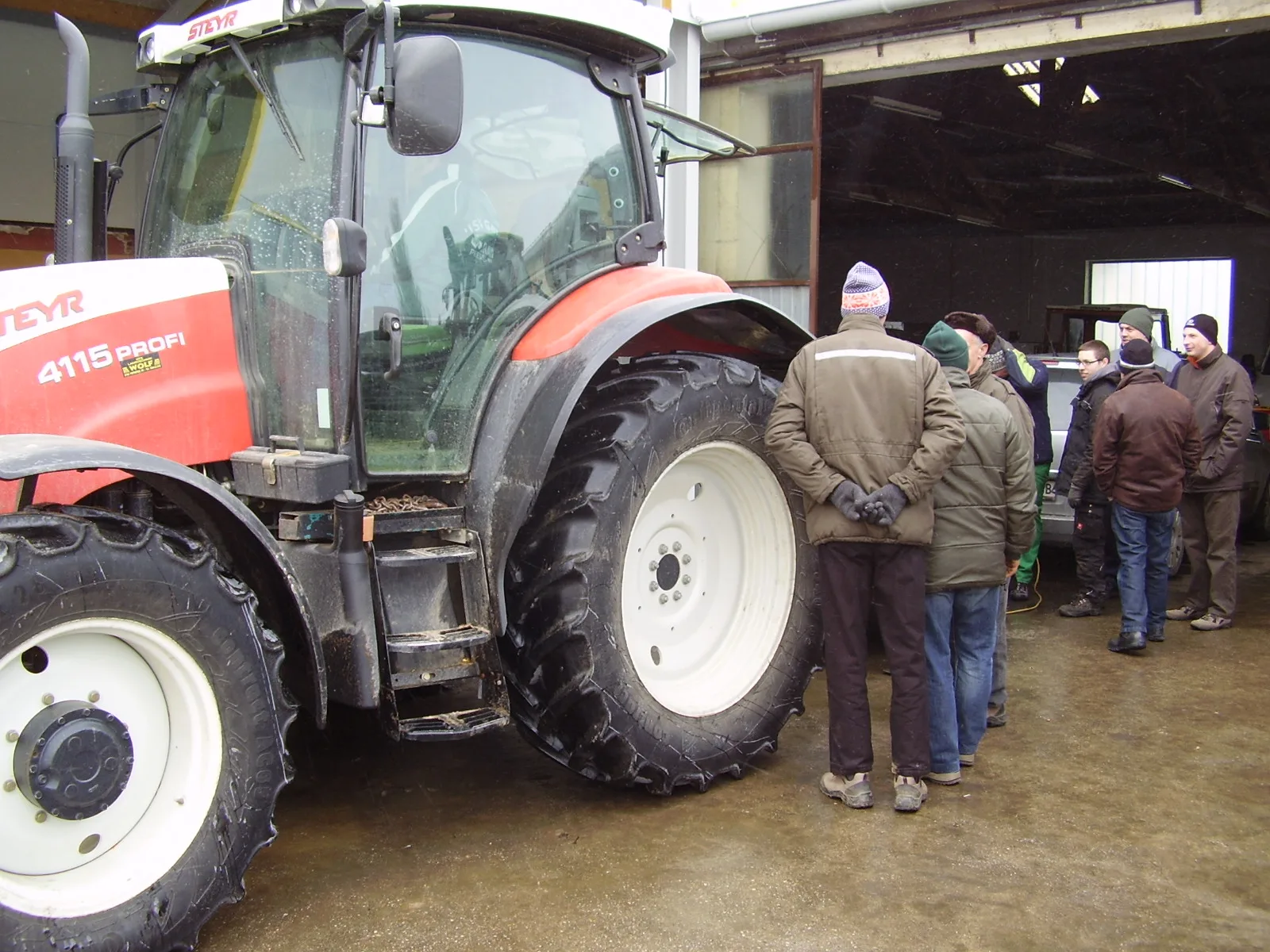 Roter Steyr 4115 vor der offenen Halle, daneben eine Gruppe Besucher